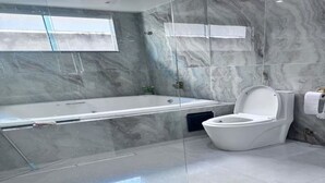 Une salle de bain moderne avec une douche à parois de verre, une baignoire blanche et des toilettes.