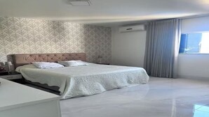 Une chambre à coucher comprenant un lit, une table de chevet, un bureau, un mur décoré d’un motif, un appareil de climatisation et une fenêtre avec des rideaux.