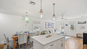 A modern kitchen with white cabinetry, a central island, and pendant lighting.