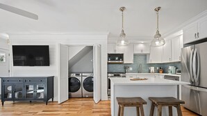 A modern kitchen with a central island, stainless steel appliances, and wooden flooring.