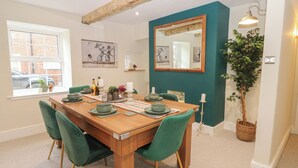 A dining area with a wooden table, green chairs, and a mirror on the wall. - Broadwath Old House (Brampton)