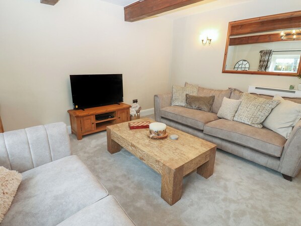 A living room with a television, sofa, coffee table, and a mirror on the wall. - Broadwath Old House (Brampton)