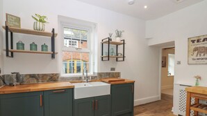 A modern kitchen with a central island, wooden countertops, and green cabinetry. - Broadwath Old House (Brampton)