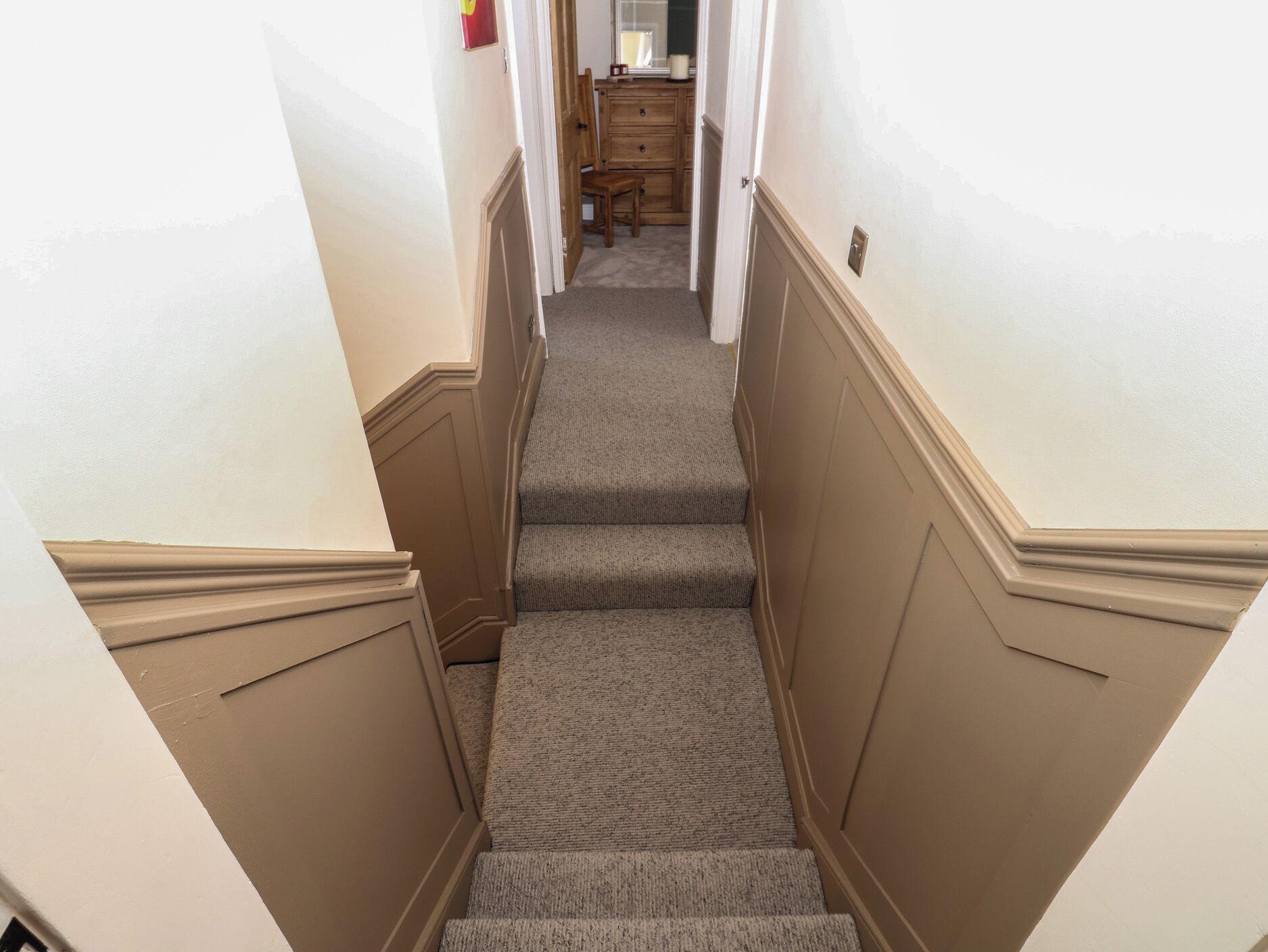 A carpeted staircase with a wooden door at the top.