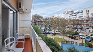 Un balcon donnant sur un parking, une piscine et les bâtiments environnants.