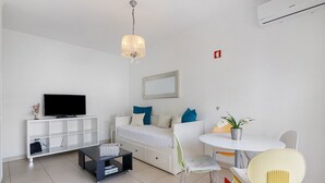 Un salon moderne comprenant un téléviseur, un canapé, une table basse et un coin repas.