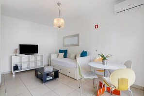 Ein modernes Wohnzimmer mit Fernseher, Sofa, Couchtisch und Essbereich.