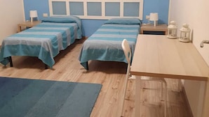 A room with two beds, a desk, a chair, a small table, and a painting on the wall. - Apartment with TERRACE ON THE SEAwith breathtaking views. 50 meters from the beach (Gela)