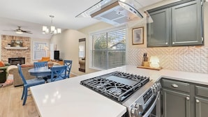 A modern kitchen with a central island, a gas stove, and dark cabinets. - Spacious Home + Hot tub + Fire Pit + Play Loft (Cedar Park)