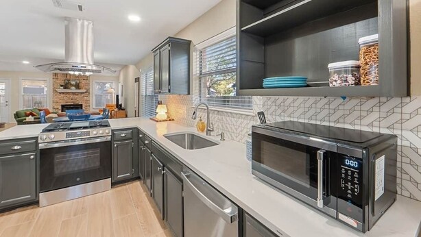 A modern kitchen with a built-in oven, microwave, and stainless steel cabinets. - Spacious Home + Hot tub + Fire Pit + Play Loft (Cedar Park)