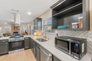 A modern kitchen with a built-in oven, microwave, and stainless steel cabinets. - Spacious Home + Hot tub + Fire Pit + Play Loft (Cedar Park)