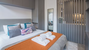 Una habitación de hotel moderna con cama, almohadas, espejo y un panel divisor.