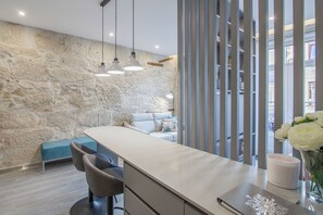 A modern kitchen with a stone wall, a bar area, and a seating space. - Ribeira Apartments Baixa (Porto)