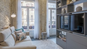 Una sala de estar con un sofá, un televisor y una estantería.