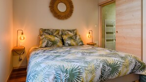 Un dormitorio con cama, un espejo redondo fijado a la pared, dos lámparas de noche y una puerta de madera.