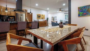 A modern kitchen with granite countertops, wooden cabinets, and a dining area with a large table and chairs. - Private pool rooftop and BBQ, Malecon 5 min walk (La Paz)