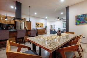 A modern kitchen with granite countertops, wooden cabinets, and a dining area with a large table and chairs. - Private pool rooftop and BBQ, Malecon 5 min walk (La Paz)