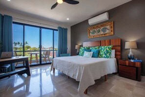 A hotel room with a bed, desk, and chair, large windows, and an air conditioning unit. - Private pool rooftop and BBQ, Malecon 5 min walk (La Paz)