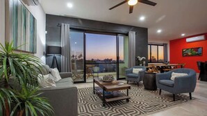 A modern living room with a sofa, armchairs, a coffee table, and a view of the cityscape through large windows. - Private pool rooftop and BBQ, Malecon 5 min walk (La Paz)
