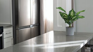 Een keuken met een roestvrijstalen koelkast, een potplant en een moderne lamp.