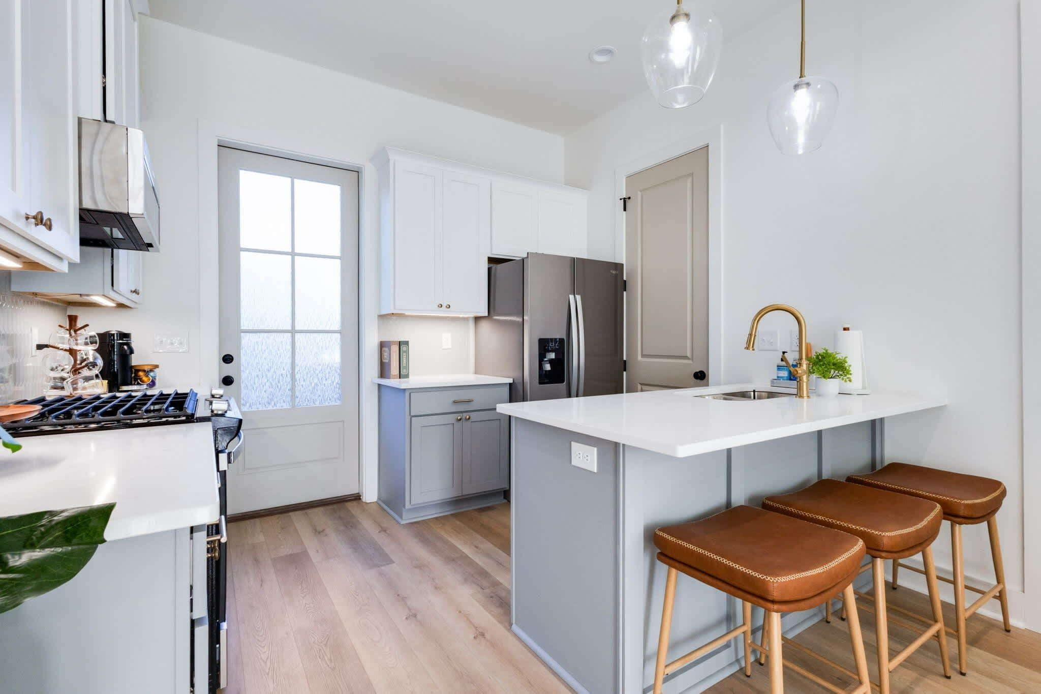 Una cocina moderna con armarios blancos, una isla grande y un refrigerador de acero inoxidable.