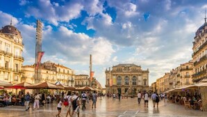 Una piazza pubblica con edifici storici, posti a sedere all'aperto e una fontana di rilievo.