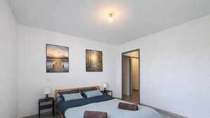 Una camera da letto con un letto, due comodini, un tavolino e due quadri appesi al muro.