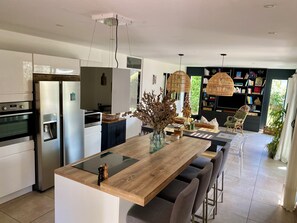 Una cocina moderna con una isla central, electrodomésticos integrados y un comedor con sillas y mesa.