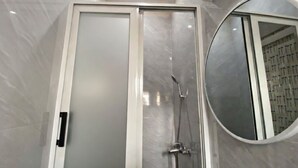 A modern bathroom with a glass shower enclosure, a frosted glass door, and a round mirror. - Magnificent residence with luxury concierge service in Brazzaville (Brazzaville)