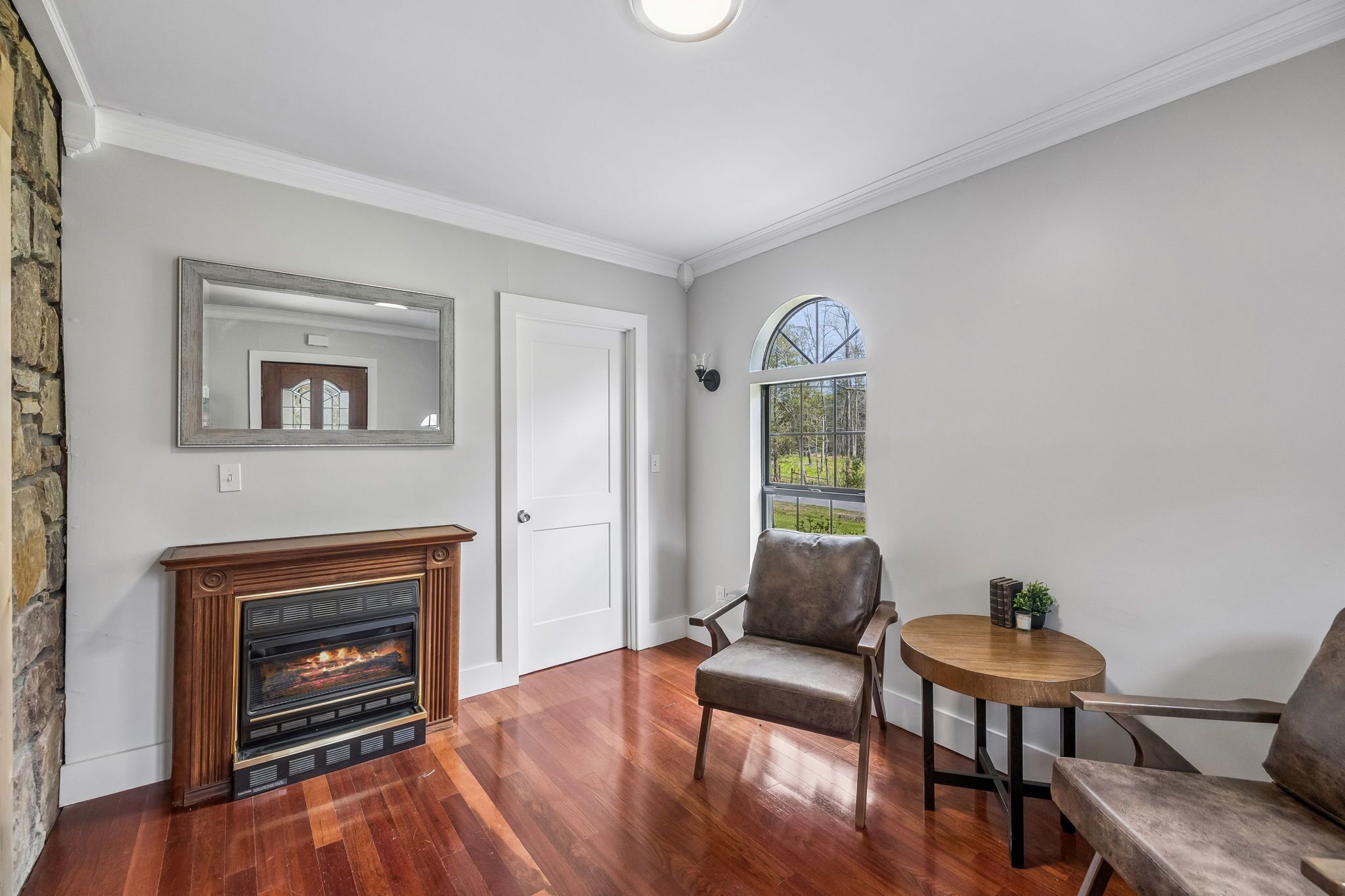 A room with a fireplace, a chair, a small table, and a window with a view.
