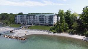 Ein mehrgeschossiges Hotel mit flachem Dach in der Nähe eines Strandes mit felsigem Ufer und klarem Wasser.