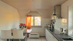 A kitchen with a window, a table with chairs, a plant, and a stove.