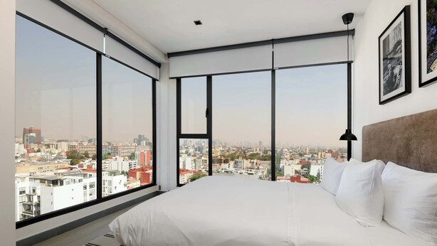 Een slaapkamer met een groot bed, uitzicht over de stad en een modern design.