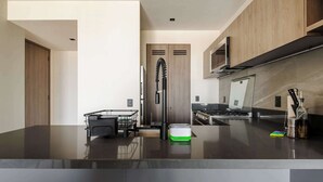 Een moderne keuken met een zwart aanrecht, roestvrijstalen apparatuur en houten kastjes.