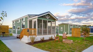 A two-story house with a porch, a small garden, and a fire pit. - Luray RV Resort on Shenandoah River (Luray)