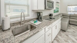 A modern kitchen with granite countertops, stainless steel sink, white cabinets, a microwave, and a coffee maker. - Luray RV Resort on Shenandoah River (Luray)