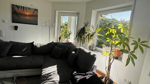 Ein Wohnzimmer mit einer Couch, einem Gemälde und Topfpflanzen.