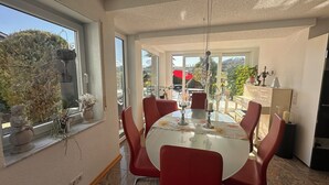 Un comedor con una mesa redonda, sillas rojas y vistas al exterior.