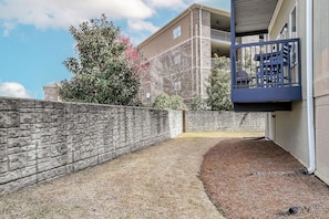 A stone wall, a grassy area, and a building with a balcony.