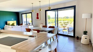 A modern living space with a dining area, sofa, and large windows with a view of greenery. - Villa César "a haven of peace with breathtaking views (Chusclan)