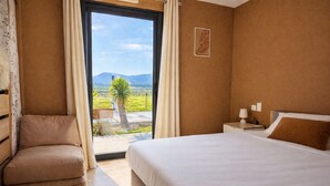 A hotel room with a bed, a chair, a nightstand, and a view of a landscape through a window. - Villa César "a haven of peace with breathtaking views (Chusclan)