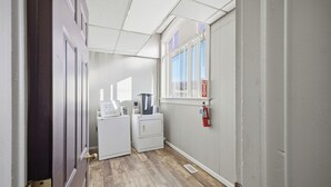 A laundry room with a washing machine, dryer, and ironing station. - Cozy 1-bedroom apartment in peaceful Wathena with AC (Wathena)