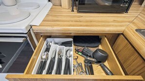 A kitchen drawer with utensils, a microwave, and a stove. - Cozy 1-bedroom apartment in peaceful Wathena with AC (Wathena)