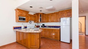 Una cocina con armarios de madera, microondas, estufa y refrigerador.