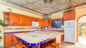 A kitchen with a tiled island, wooden cabinets, a microwave, and a refrigerator. - Cozy, Quiet & Beautiful Home Borracho Flat (Bahía la Choya)