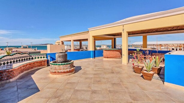 A rooftop terrace with a blue wall, tiled floor, and potted plants. - Cozy, Quiet & Beautiful Home Borracho Flat (Bahía la Choya)