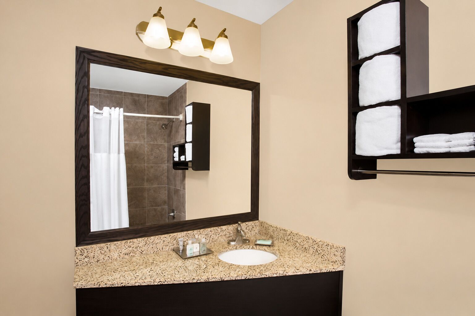 Une salle de bain avec un grand miroir, un lavabo et un porte-serviettes.