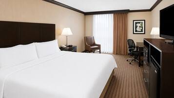 Une chambre d’hôtel avec un grand lit, un bureau avec une télévision, une chaise et une lampe de bureau.