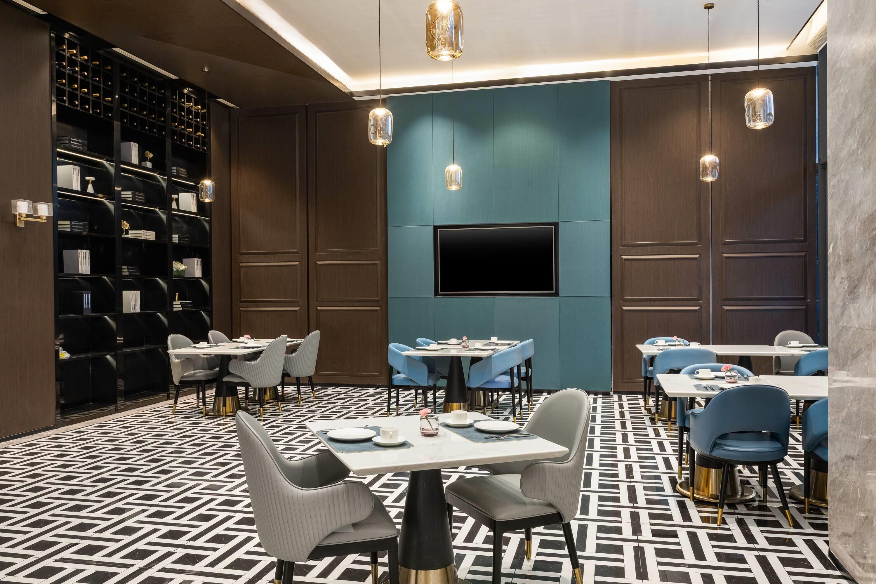 A modern dining area with tables, chairs, a TV screen, and a wine rack.