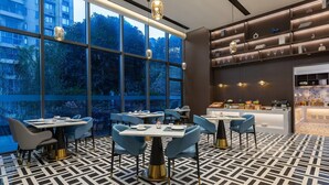 A modern restaurant with large windows, geometric floor tiles, and contemporary furniture.